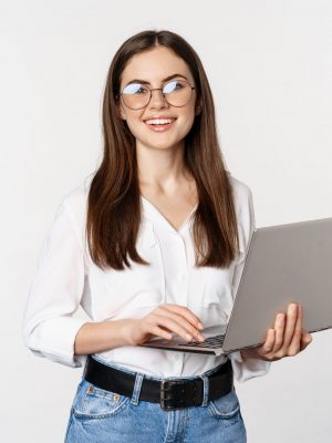 Portrait of young office woman, entrepreneur answer clients on laptop, working with computer with happy face, standing over white background.